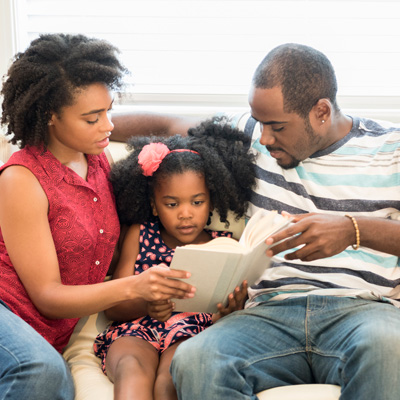 Black couple with child reading book